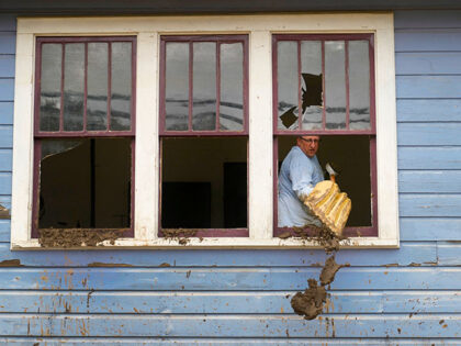 Ben Phillips scoops mud out a window of his house left in the wake of Hurricane Helene, Tu