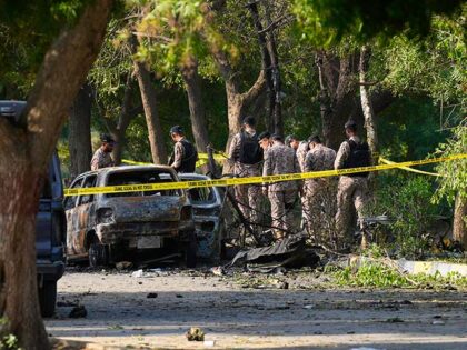 Security officials work on the site of an explosion that caused injures and destroyed vehi