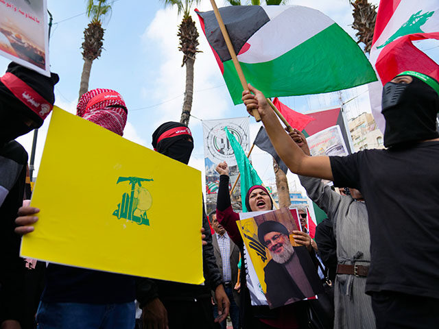 Palestinian activists chant slogans as they hold posters with pictures of late Hezbollah l