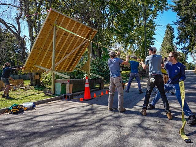 Volunteers work to lower the roof of a platform that will be used to provide water from a