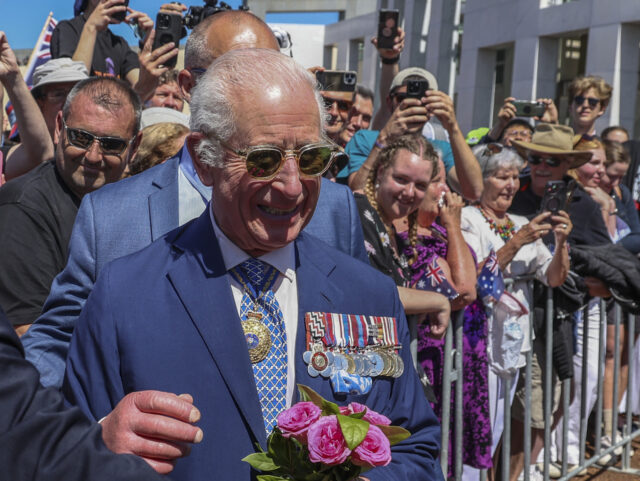 Britain's King Charles III receives a bouquet of roses as he meets members of the pub