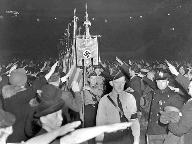 The crowd responds with a Hitler salute as uniformed members of a German-American Bund col