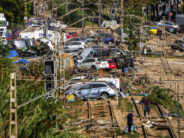 People walk among flooded cars piled up in Valencia, Spain, Thursday, Oct. 31, 2024. (AP P