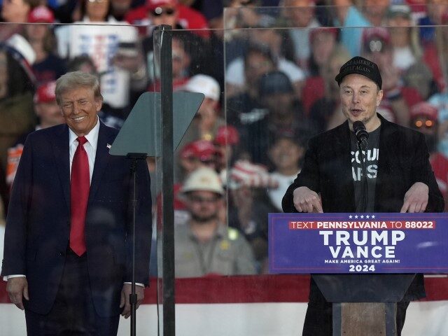 Republican presidential nominee former President Donald Trump listens as Elon Musk speaks