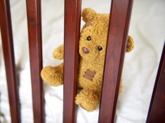 Empty crib with teddy bear