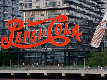 People walk along the East River in front of the iconic Pepsi - Cola sign in Long Island C