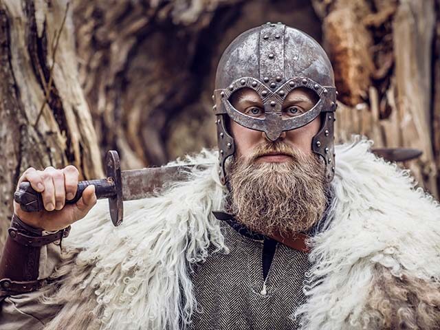 weapon wielding viking rus warrior outdoors in a wintry forest scene in the morning sun