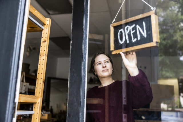 Female small business owner turning open sign in her store