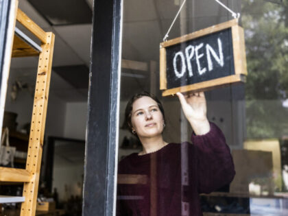 Female small business owner turning open sign in her store