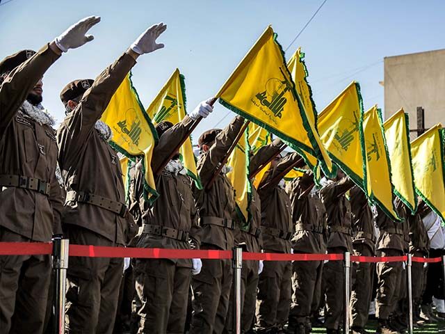 Hezbollah members salute and raise the group's yellow flags during the funeral of their fa