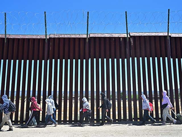 Migrants walk on the US side of the border wall in Jacumba Hot Springs, California on June