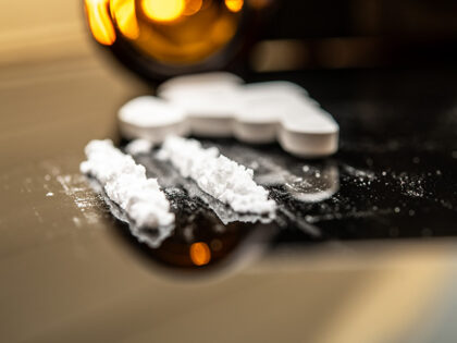 Fentanyl powder and prescription pills scattered on a reflective surface, illustrating the