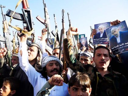 Yemenis including Houthi followers brandish rifles and placards depicting the head of the