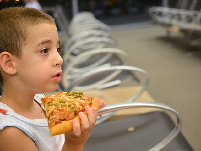 Young boy eating pizza while waiting for his flight