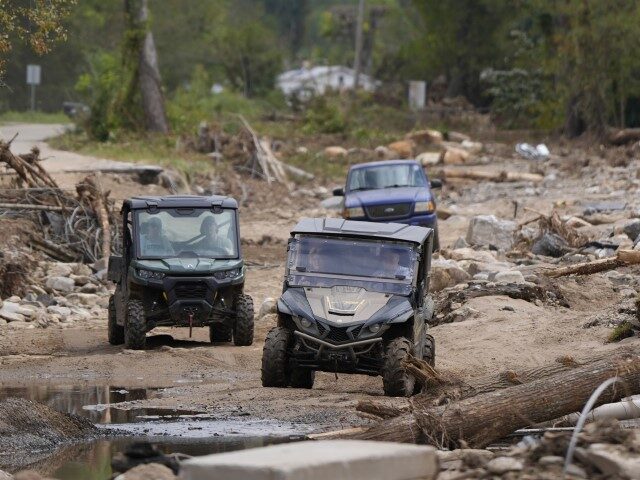 Vehicles roll along on a washed up road in the aftermath of Hurricane Helene, Thursday, Oc