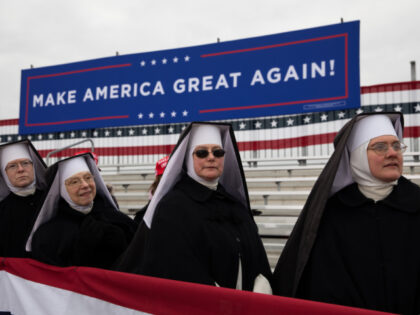 Nuns stand in front of a 'Make America Great Again' sign while waiting for the a