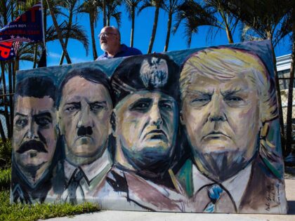 A demonstrator holds a painting featuring the likenesses of Joseph Stalin, from left, Adol