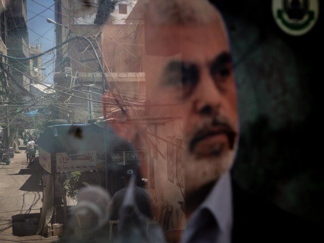 People are reflected in a window displaying a poster of newly appointed Hamas leader Yahya