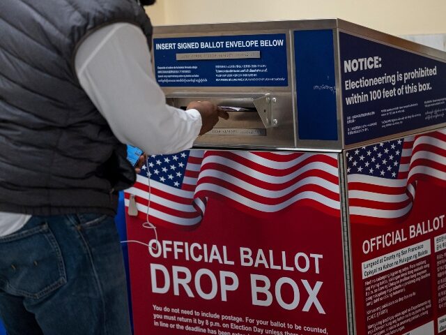 A voter submits their ballot at an official ballot drop box at a polling location in City