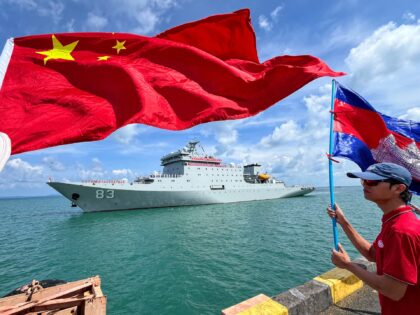 People wave flags of Cambodia (R) and China (L) as Chinese training ship Qijiguang prepare