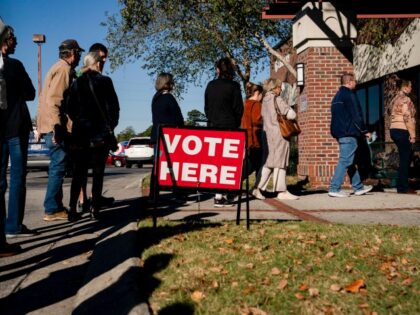 Voters wait in line to cast their ballots during the first day of early voting at a pollin