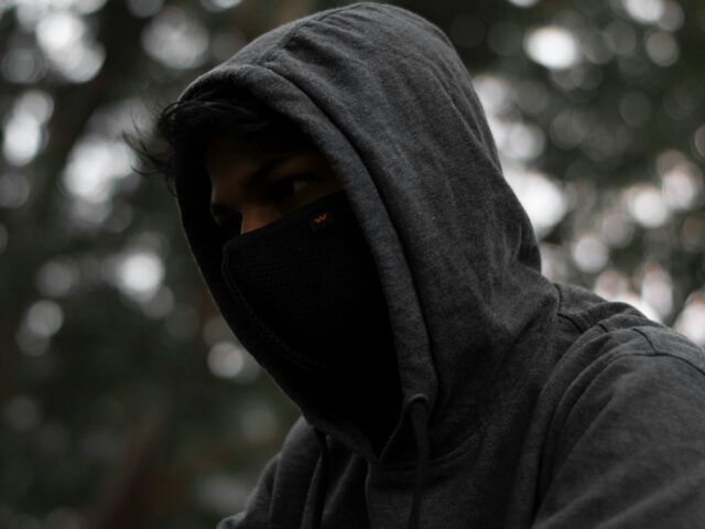 person in gray hoodie wearing black mask