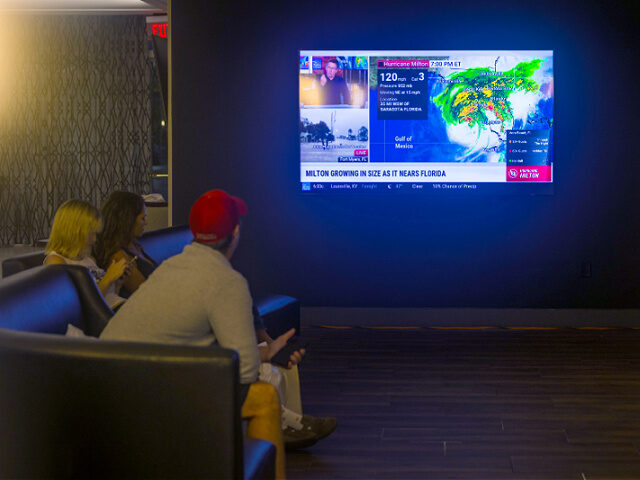 ORLANDO, FLORIDA - OCTOBER 9: People watch the weather report at a restaurant as the commu