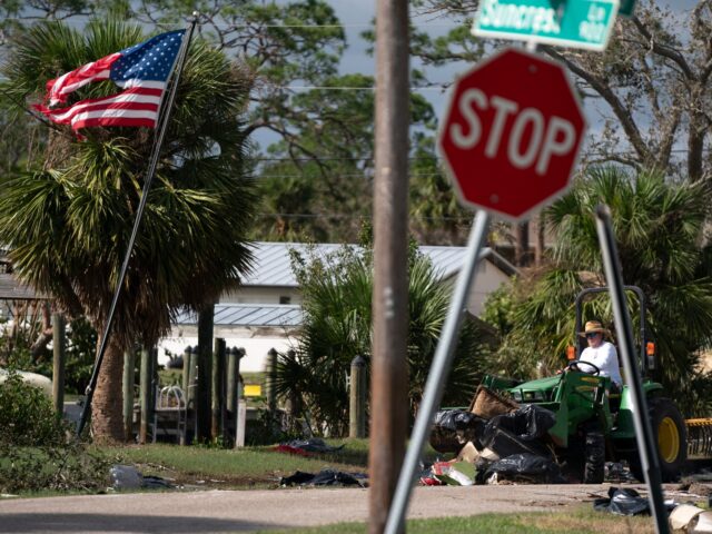 ENGLEWOOD, FLORIDA - OCTOBER 10: A man cleans storm debris using a tractor in the aftermat