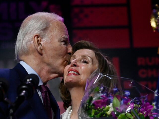 US President Joe Biden kisses honoree House Speaker Emerita Nancy Pelosi onstage during Em