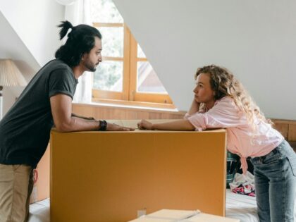 Couple inside house with moving box.