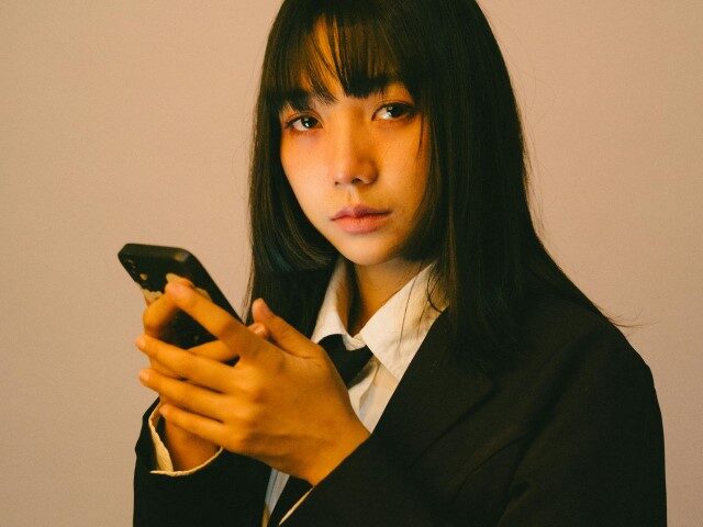 Contemplative Woman in Suit with Smartphone