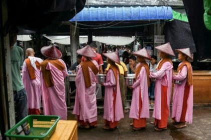 Buddhist nuns collect alms at a shop in the Jade Market in Mandalay on October 23