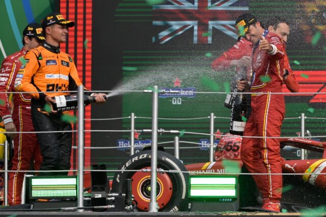 Closing in: Carlos Sainz is sprayed with champagne by Lando Norris