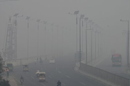 Commuters drive along a road amid heavy smog in Lahore