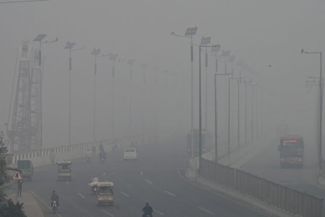 Commuters drive along a road amid heavy smog in Lahore