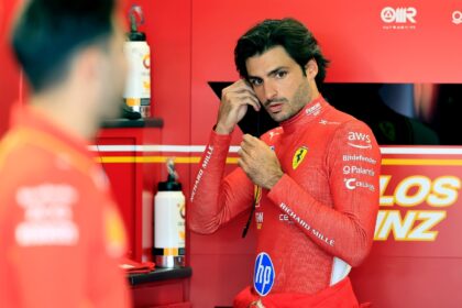 Ferrari's Spanish driver Carlos Sainz puts his headphones into his ear while in the team g