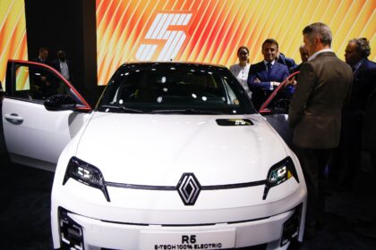 French President Emmanuel Macron stands by a new electric Renault R5 E-Tech at the Paris M