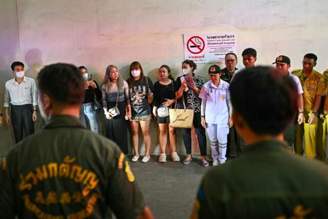 Grieving Thai relatives watch as ambulances carry the remains of victims of a school bus f
