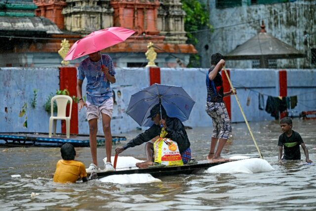 Indians make their way through a flooded street in Chennai