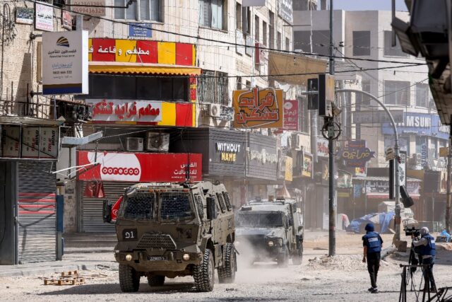 Journalists cover the deployment of Israeli armoured vehicles during a raid in the Jenin c