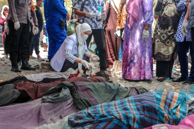 A medical official examines bodies of Rohingya refugees at a beach in Indonesia's Aceh Pro