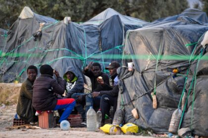 Migrants from sub-Saharan Africa sit next to makeshift shelters at a camp in Tunisia