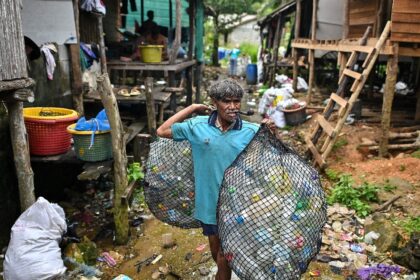 A Moken fisherman carries bags of plastic waste to sell to Tide staff members at his fishi