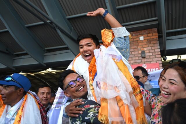 Nepali mountaineer Nima Rinji Sherpa waves upon his arrival in Kathmandu after breaking th