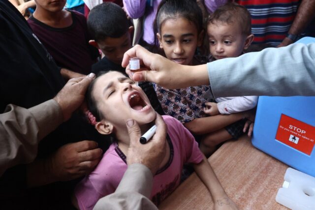 Palestinian children receive drops as part of a polio vaccination campaign in Deir al-Bala