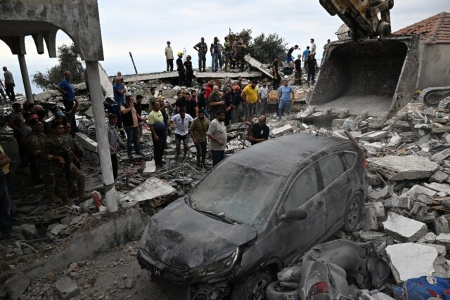 People inspect the damage at the site of an Israeli air strike on Maaysra