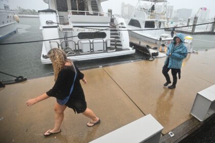 People walk along the marina of Sarasota, Florida as powerful Hurricane Milton nears the c