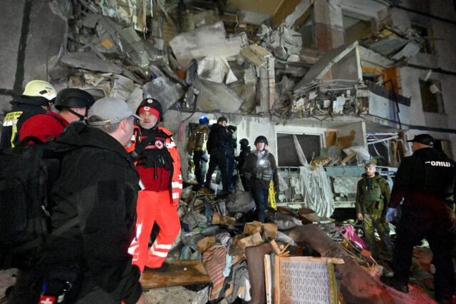 Police officers, medics and rescuers work in a damaged apartment building in Kharkiv hit b