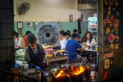 The Queen of Street Food and Michelin star chef Jay Fai (L foreground) cooks at her restau