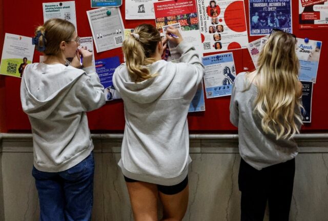 Students fill out registration forms as they take advantage of early voting in the 2024 US